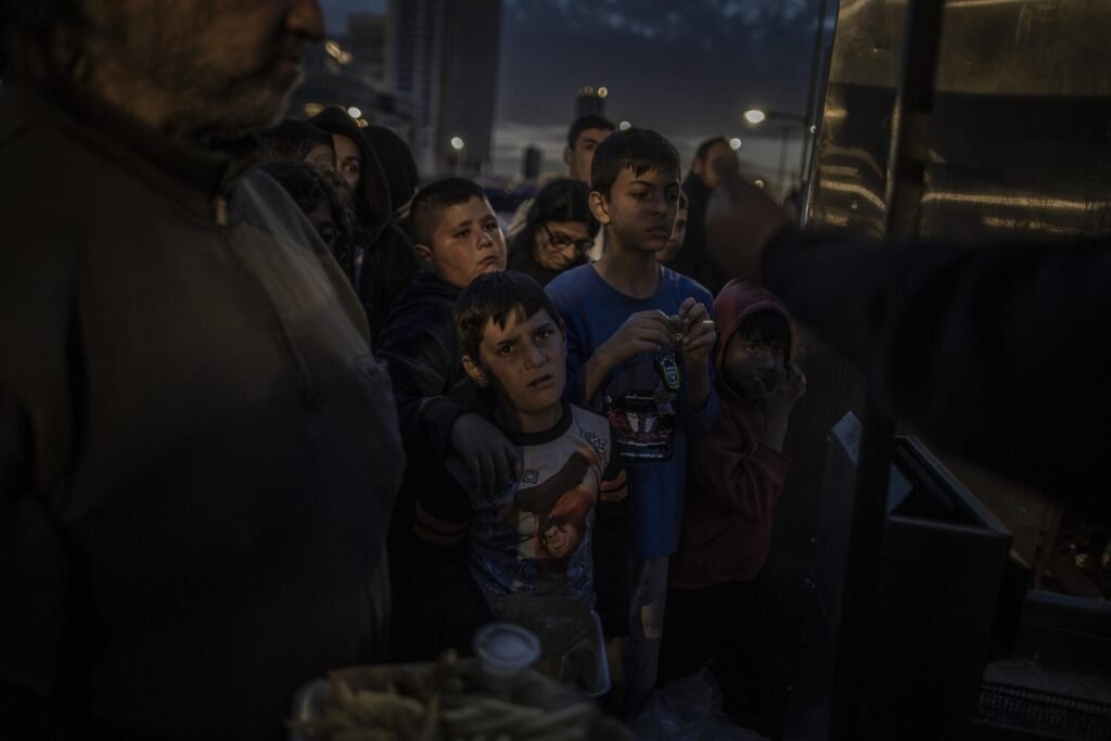 Un grupo de niños desplazados de su hogar por los recientes ataques israelíes esperan recibir una ración de comida en la ciudad de Beirut.