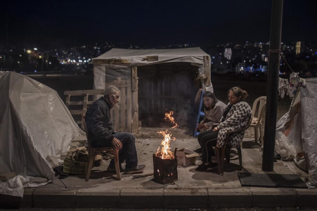 Un grupo de personas desplazadas de Dahie, al sur de Beirut, se agrupa alrededor de una hoguera frente a su tienda de campaña para combatir el frío.