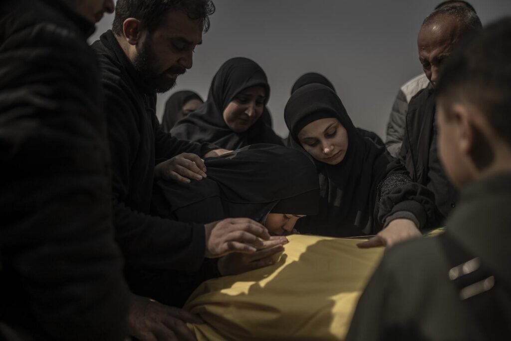 Familiares de un paramédico libanés se despiden de él en su funeral en el sur de Beirut en un cementerio improvisado esperando poder enterrarlo en un lugar seguro.