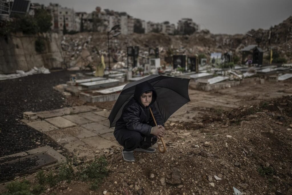 Un niño se resguarda de la lluvia bajo un paraguas durante el funeral de los periodistas Ali Shoeib, Fátima Ftouni y Mohamed Ftouni, asesinados en un bombardeo israelí en el sur del Líbano.