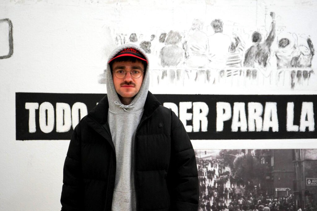 Mateo Zikuta, tras la entrevista, frente a un mural de la exposición «Todo el poder para la asamblea», sobre el 3 de marzo de 1976 en Vitoria-Gasteiz.