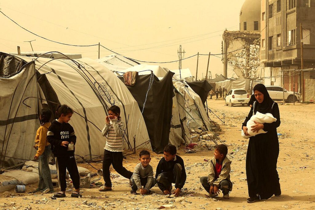 Palestinos que perdieron sus hogares en la reciente guerra son vistos cerca de sus tiendas de campaña en Khan Yunis, en el sur de la Franja de Gaza.
