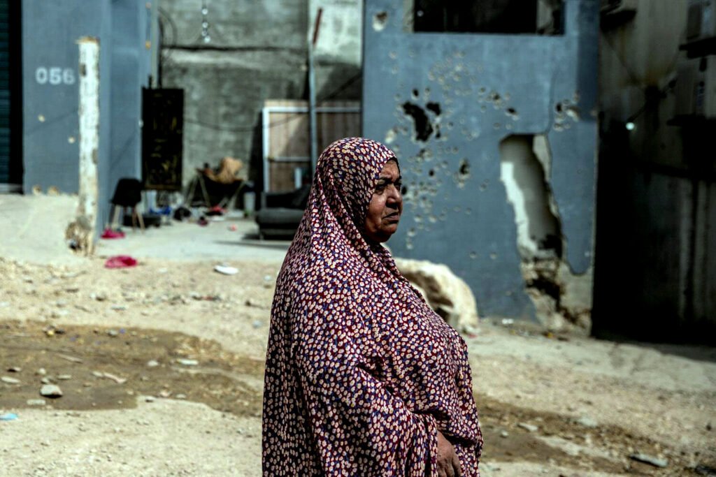 Una mujer camina alrededor de las paredes acribilladas por balas de una casa en las afueras del campo de refugiados de Tulkarem.