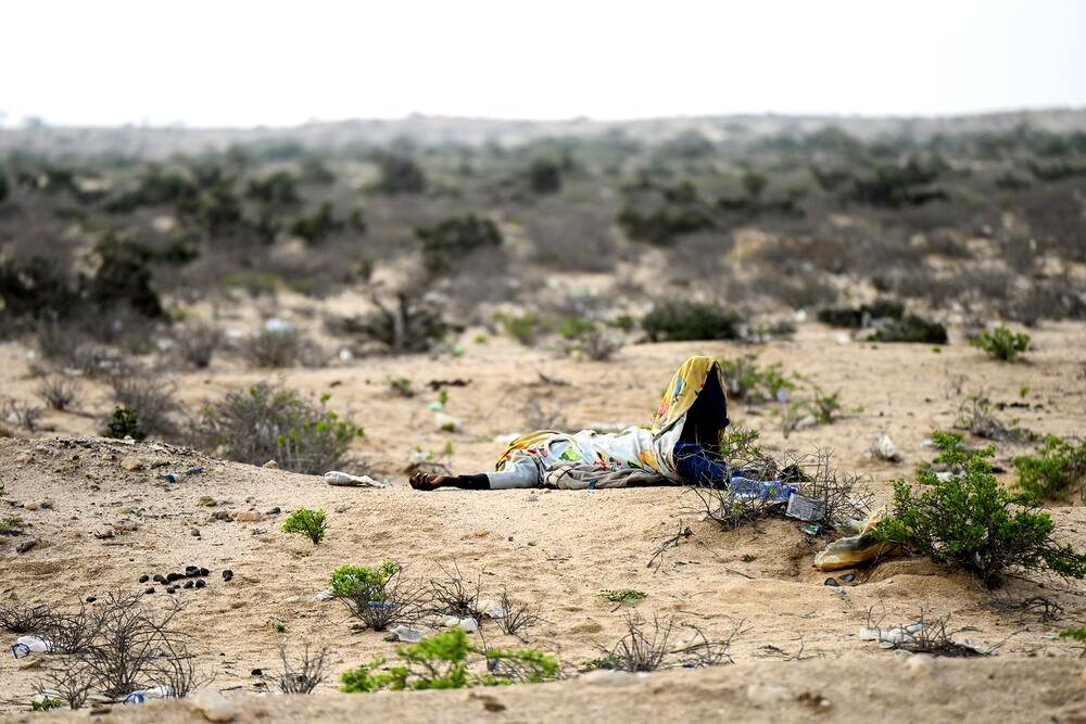 Una persona, de las decenas de migrantes que a diario caminan por la ruta que une Hargeisa con la costa, descansa junto a la carretera.