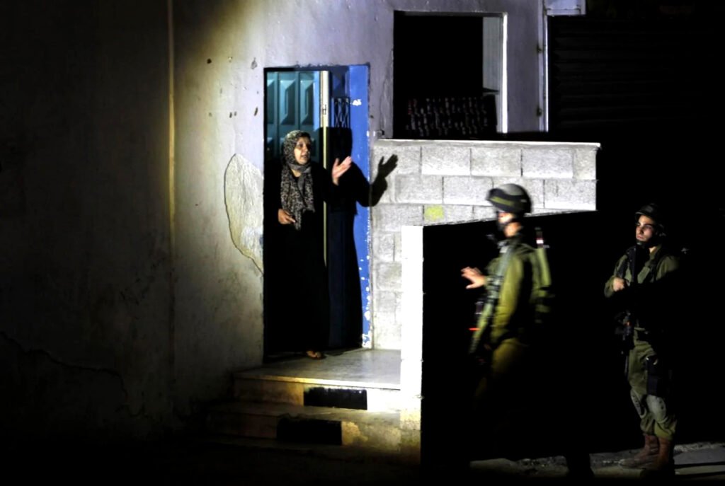 Soldados israelíes interrogan a una mujer palestina durante una redada nocturna en el campo de refugiados de Jalazun, en la Cisjordania ocupada, al norte de Ramala,