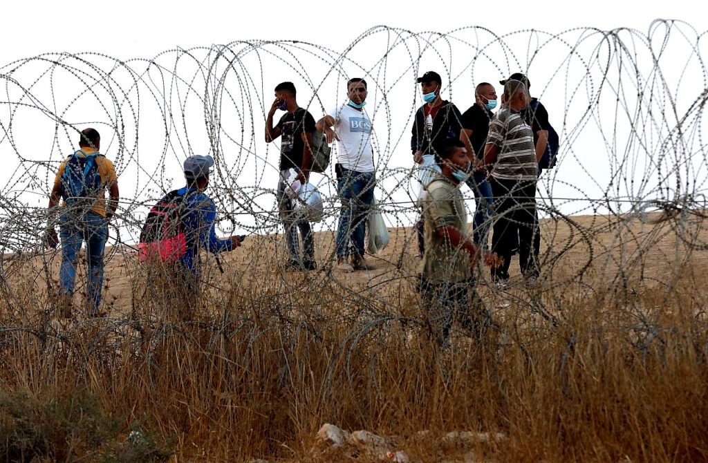 Trabajadores palestinos cruzan ilegalmente a Israel buscando trabajo a través de un agujero en una valla en las afueras de Hebrón, Cisjordania,