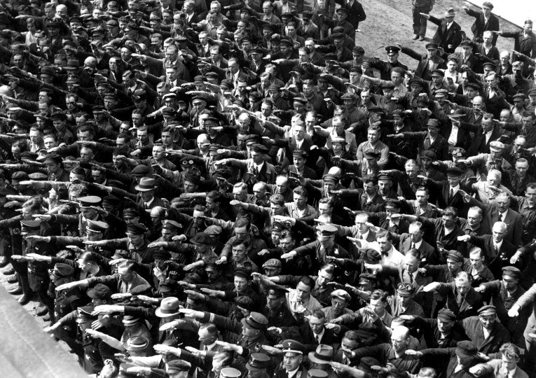 Docenas de obreros alemanes realizan el saludo nazi en junio de 1936 mientras uno de ellos permanece cruzado de brazos.