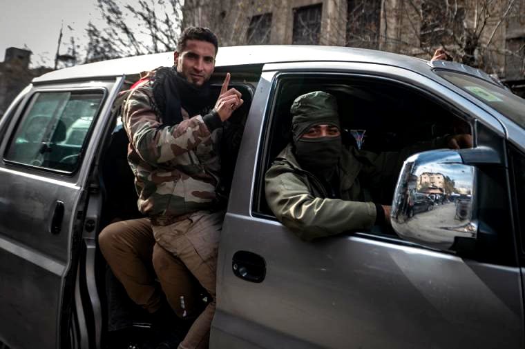 Milicianos celebran la caída del régimen de Asad en un coche por las calles de Damasco.
