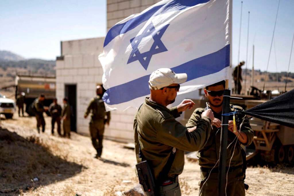Soldados del ejército israelí colocan bridas de plástico en el mástil de una bandera israelí que ondea en una zona especial para ejercicios militares durante una maniobra militar en los Altos del Golán.