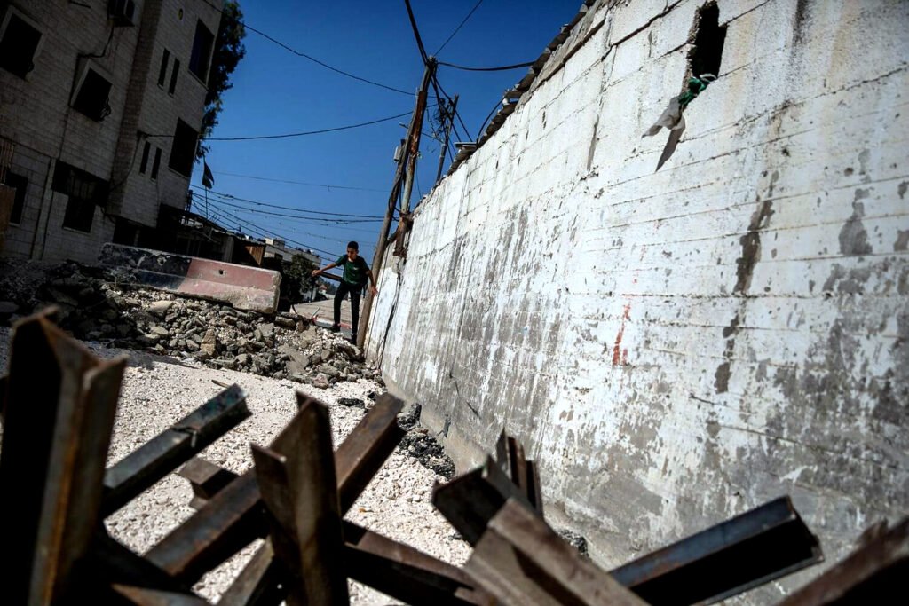 Un niño salta una barricada en el campo de refugiados de Yenín.