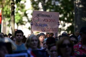 Una mujer sostiene un cartel en defensa del pueblo palestino y contra el genocidio gazatí.