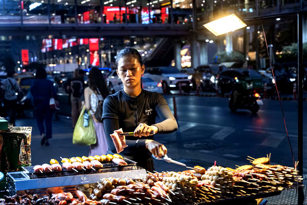 Una mujer tailandesa cocina carne en un puesto de comida callejera, en Bangkok, en marzo de 2025.
