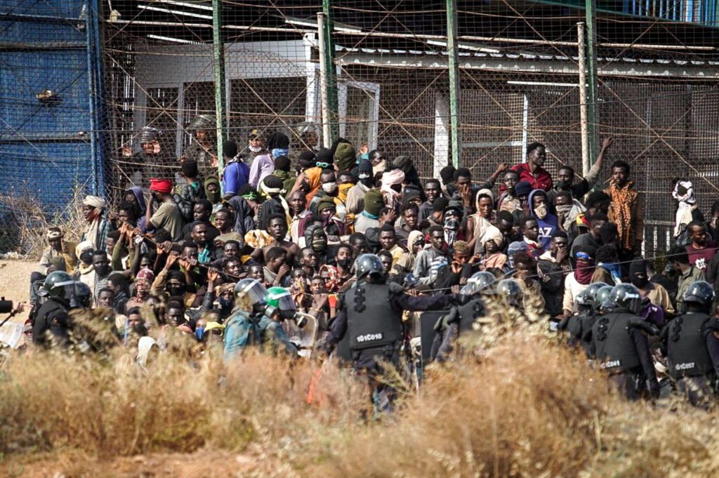 Varias decenas de personas, en la valla de Melilla durante el salto del 24 de junio de 2022.