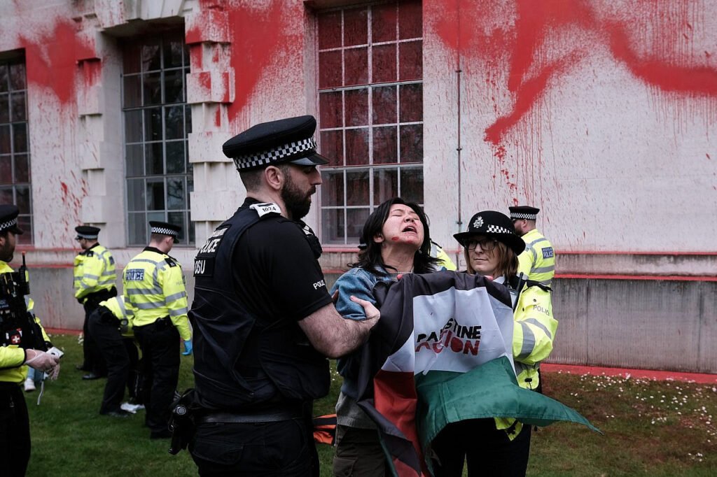 La policía detiene a un militante después de que activistas de Palestine Action rociaran pintura roja en las paredes del Ministerio de Defensa del Reino Unido para denunciar la complicidad británica en el genocidio de Gaza. Londres.