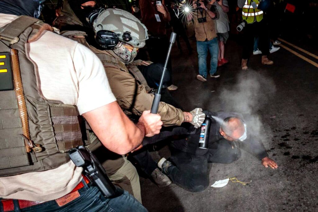 Agentes del ICE rocían a un manifestante con un irritante químico antes de detenerlo a las afueras del centro federal de inmigración en Delaney Hall, donde el ICE aloja a inmigrantes detenidos.
