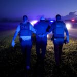 Dos agentes del ICE se llevan a un hombre detenido en Florida, en octubre de 2025.