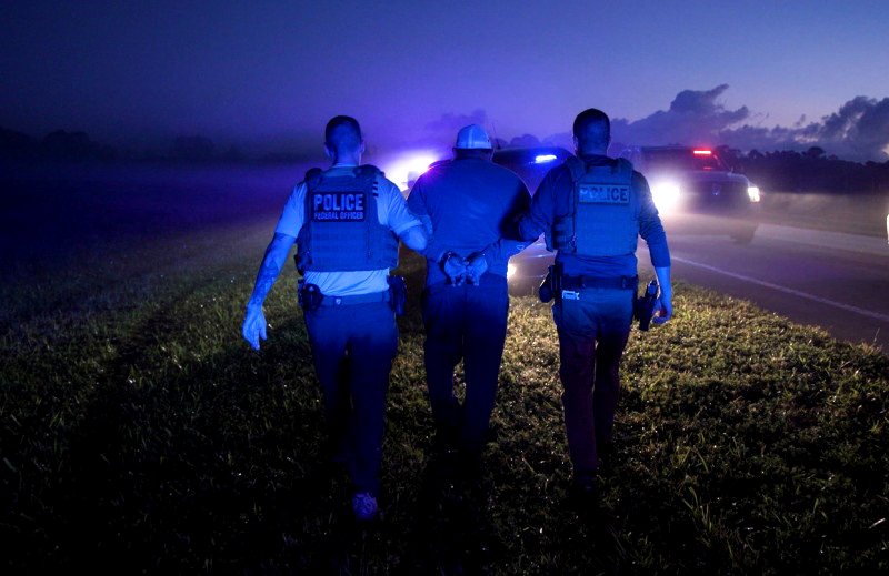 Dos agentes del ICE se llevan a un hombre detenido en Florida, en octubre de 2025.