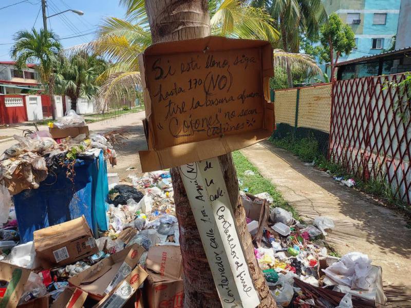 Un cartel pide ir al siguiente contenedor para evitar la acumulación de basura.