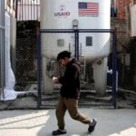 Un hombre pasa junto al tanque de almacenamiento de oxígeno líquido instalado en el Hospital Bir por la USAID, en Katmandú, Nepal.