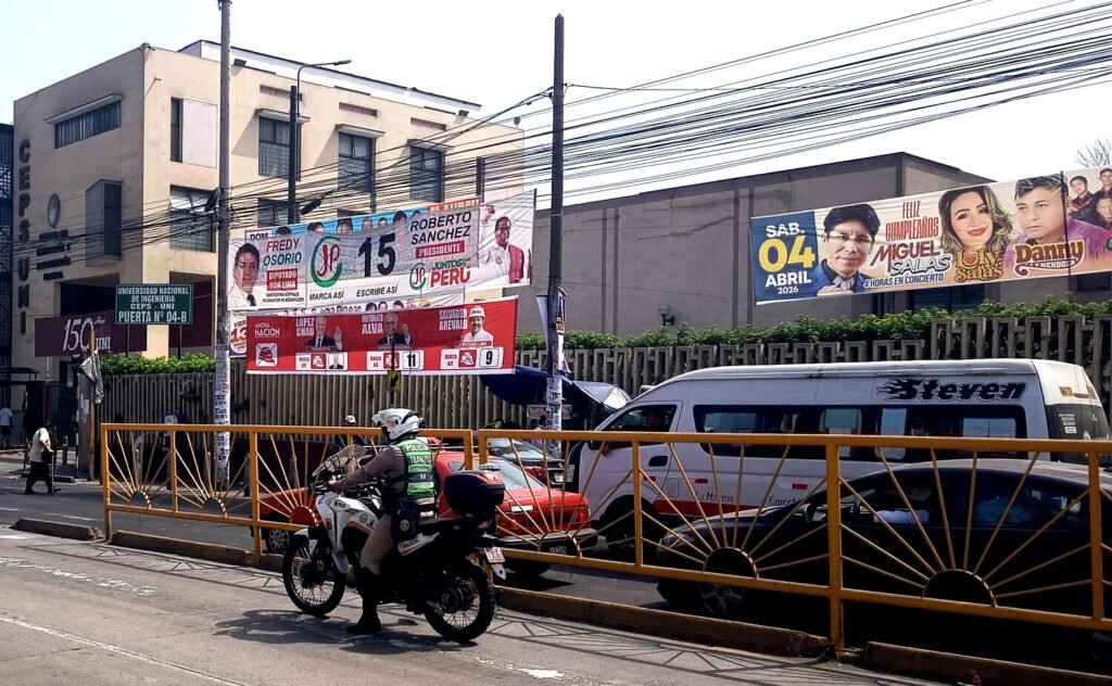 Un policía, frente a la propaganda electoral de Juntos por el Perú y Ahora Nación, las dos principales formaciones de izquierda