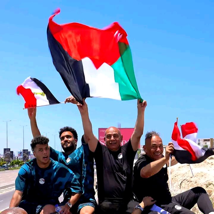 El seleccionador egipcio Hossam Hassan ondea una bandera palestina mientras saluda a los aficionados reunidos en el Aeropuerto Internacional de El Alamein tras la histórica participación de su equipo en la Copa Mundial de la FIFA, Egipto, 10 de julio de 2026.