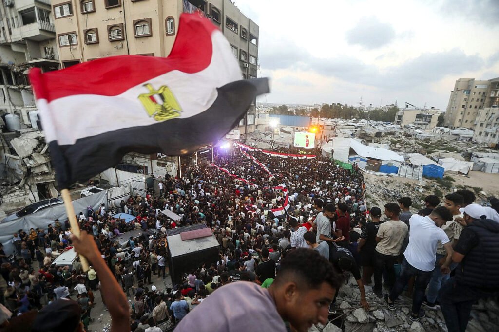 Palestinos desplazados observan el partido de la Copa Mundial de la FIFA entre Egipto y Argentina en una pantalla gigante mientras se sientan entre los escombros de edificios destruidos en el centro de la ciudad de Gaza, el 7 de julio de 2026.