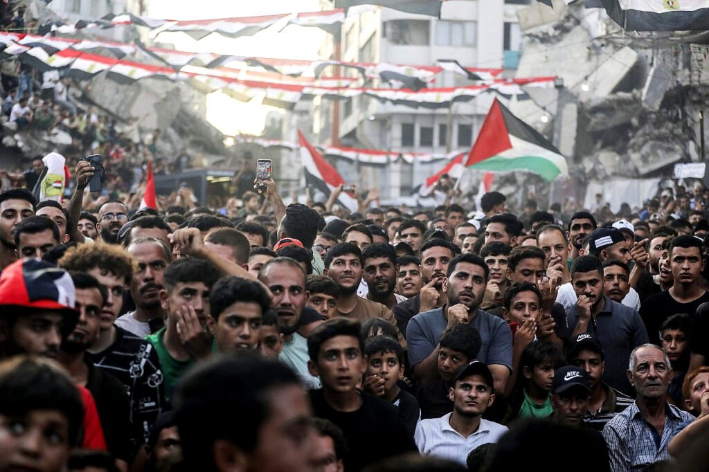 Palestinos desplazados observan el partido de la Copa Mundial de la FIFA entre Egipto y Argentina en una pantalla gigante mientras se sientan entre los escombros de edificios destruidos en el centro de la ciudad de Gaza, el 7 de julio de 2026.