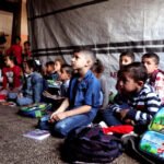 Alumnos sentados en el suelo mientras asisten a clase en una escuela de educación primaria gestionada por la UNRWA.