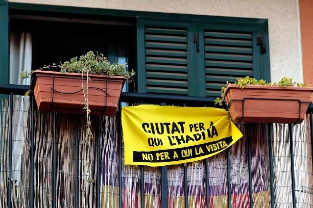 Una pancarta con el lema 'Ciudad para quien la habita, no para quien la visita' colgada de un balcón del barrio de Santa Catalina, en Palma.