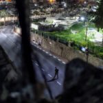 Desde una ventana de las pocas casas palestinas en la zona H2 de la ciudad vieja. Un colono armado camina por la calle Shuhada; al fondo el cementerio palestino.