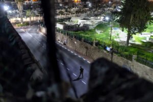 Desde una ventana de las pocas casas palestinas en la zona H2 de la ciudad vieja. Un colono armado camina por la calle Shuhada; al fondo el cementerio palestino.