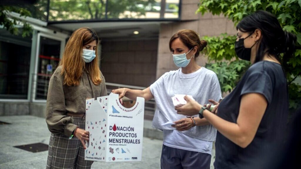 Loreto Arenillas y Mónica García el 28 de mayo de 2021 con la urna de recogida de productos de higiene menstrual que colocaron en la Asamblea