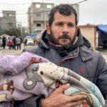 Maher Bassiouni carga el cuerpo de su hijo Mohammed, de un año, tras morir de frío en Deir al-Balah, 13 de enero de 2026.