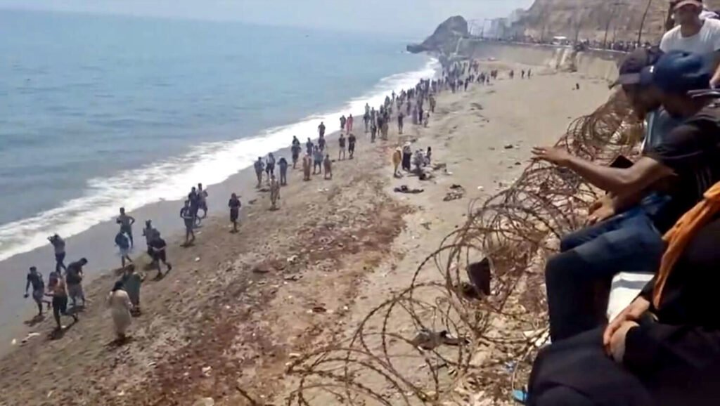 Migrantes andando por la costa de Ceuta tras pasar la frontera.