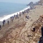 Migrantes andando por la costa de Ceuta tras pasar la frontera.