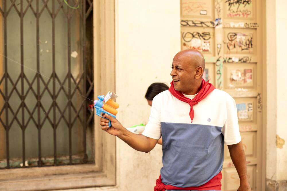 Un miembro de Negu Gorriak dispara con la pistola de agua frente a la casa de baños. Fotografía de Mikel Romeo Ruiz.