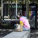 Una chica mira sus redes sociales sentada en el banco de una plaza en un municipio de Madrid - Fotografía: Álvaro Minguito.