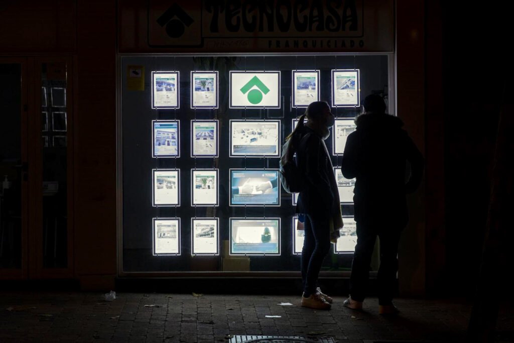 Una pareja mira anuncios de vivienda en una inmobiliaria.