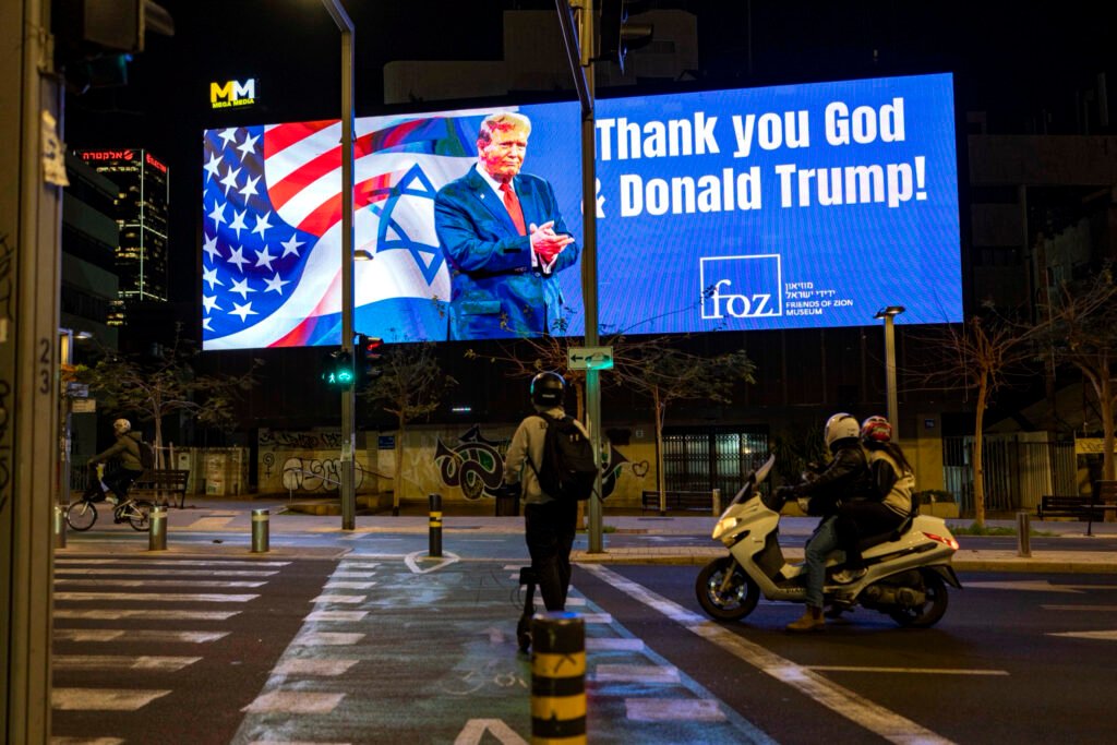 Varias personas pasan junto a un cartel que dice 'Gracias a Dios y a Donald Trump', durante la guerra entre Estados Unidos e Israel contra Irán, en Tel Aviv.