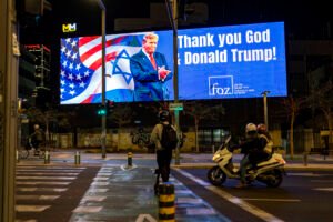 Varias personas pasan junto a un cartel que dice 'Gracias a Dios y a Donald Trump', durante la guerra entre Estados Unidos e Israel contra Irán, en Tel Aviv.
