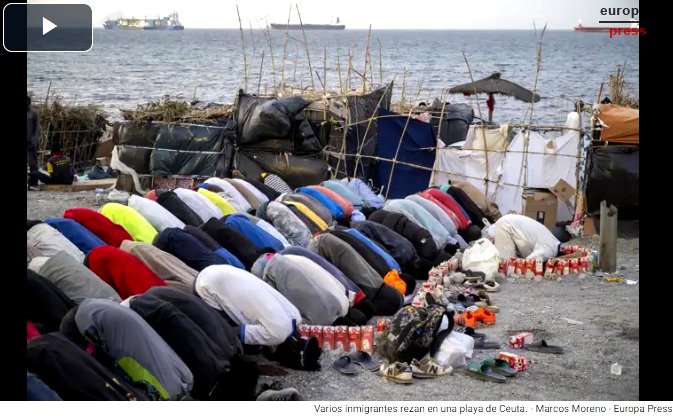 Varias personas migrantes rezan en una playa de Ceuta.