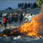 Mobiliario urbano y enseres arden en Ceuta durante una manifestación para protestar por la situación provocada por la llegada masiva de migrantes. 27.08.2026.
