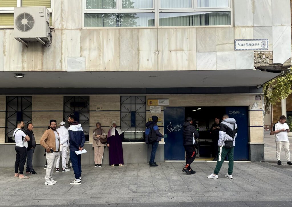 Personas esperan frente a la sede de Extranjería en Huelva a ser atendidas.