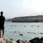 Playa Tarajal de Ceuta. Migrante recién salido del agua visualiza lo superado.