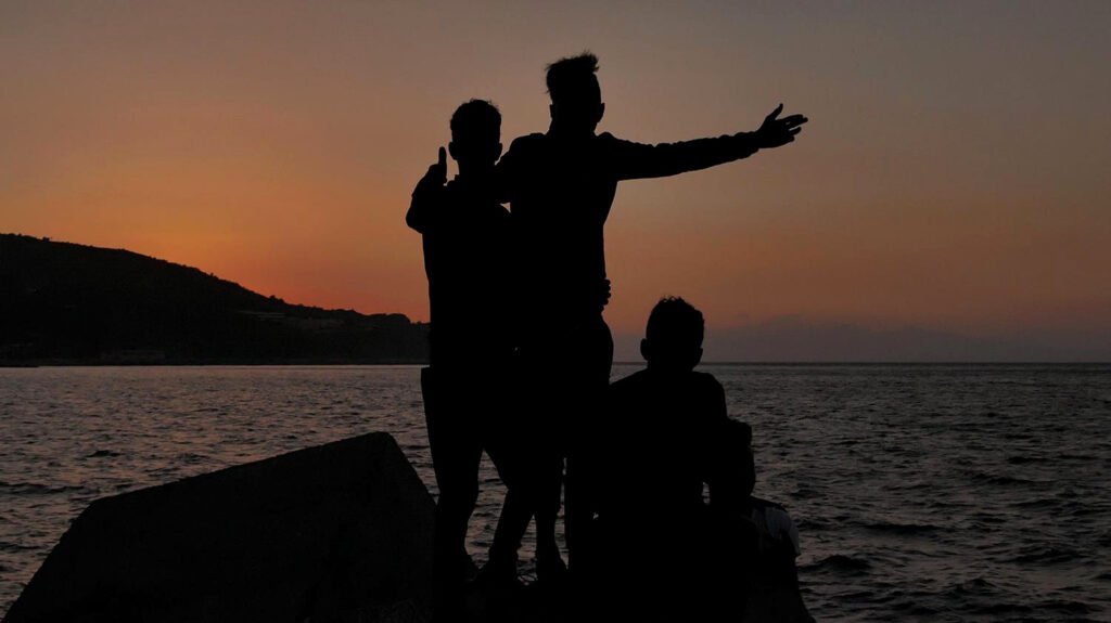 Un grupo de niños que vive en el puerto de Ceuta se hace una foto señalando la Península a lo lejos, al otro lado del Estrecho.