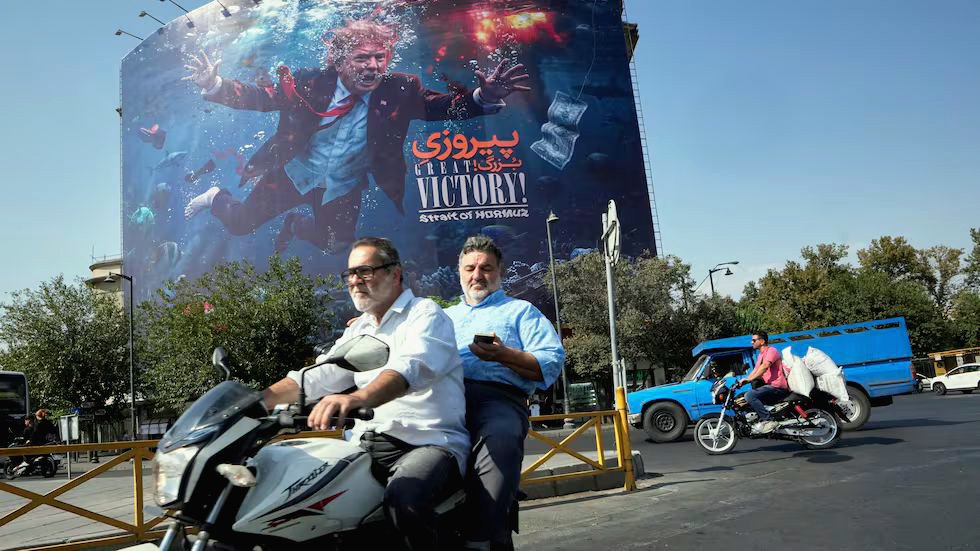Un motociclista pasa frente a un anuncio propagandístico contra Trump en Teherán, este lunes.