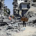 Ciudadanos recogen sus pertenencias de una calle llena de escombros en el barrio de Tuffah, en la ciudad de Gaza, junto a bloques de hormigón amarillos que marcan la «Línea Amarilla» impuesta por Israel, el 27 de julio de 2026. Youssef Zanoun/ActiveStills.