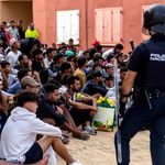 Un agente de la policía española monta guardia mientras los migrantes esperan para ser registrados en el distrito de Loma Colmenar de Ceuta el 31 de agosto de 2026.