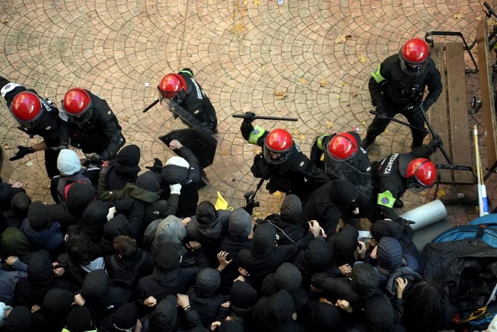 Agentes de la Ertzaintza cargan contra las personas concentradas frente al portal de la avenida de los Huetos. Mikel Bejarano.