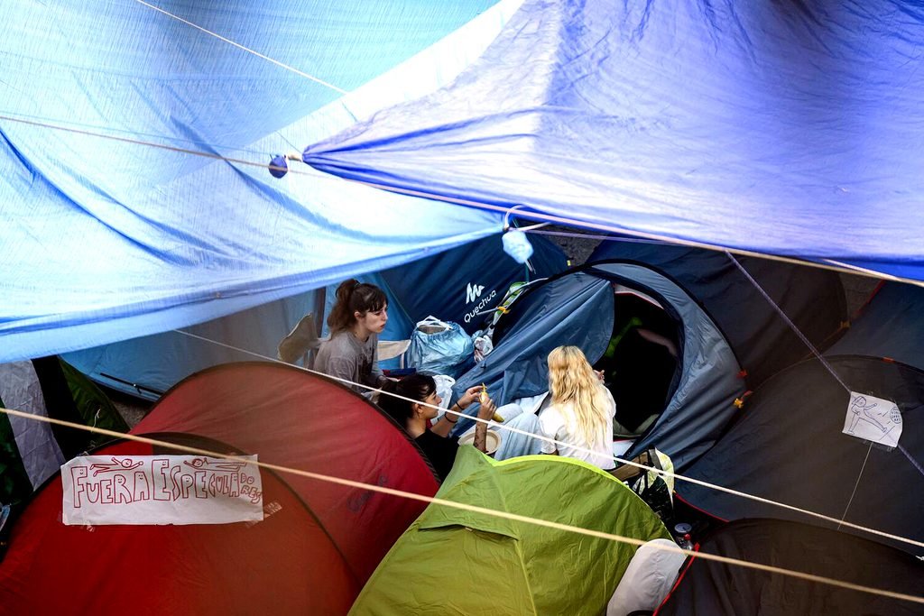 Tres personas hablan en sus tiendas de campañas en la acampada por la vivienda en Sol.
